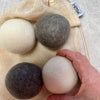 Wool Dryer Balls with organic cotton produce bag and hand holding ball