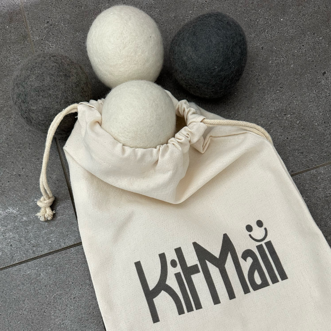 Photo of  White and Grey Wool Dryer Balls in organic cotton Kitmaii peg bag on grey tile floor